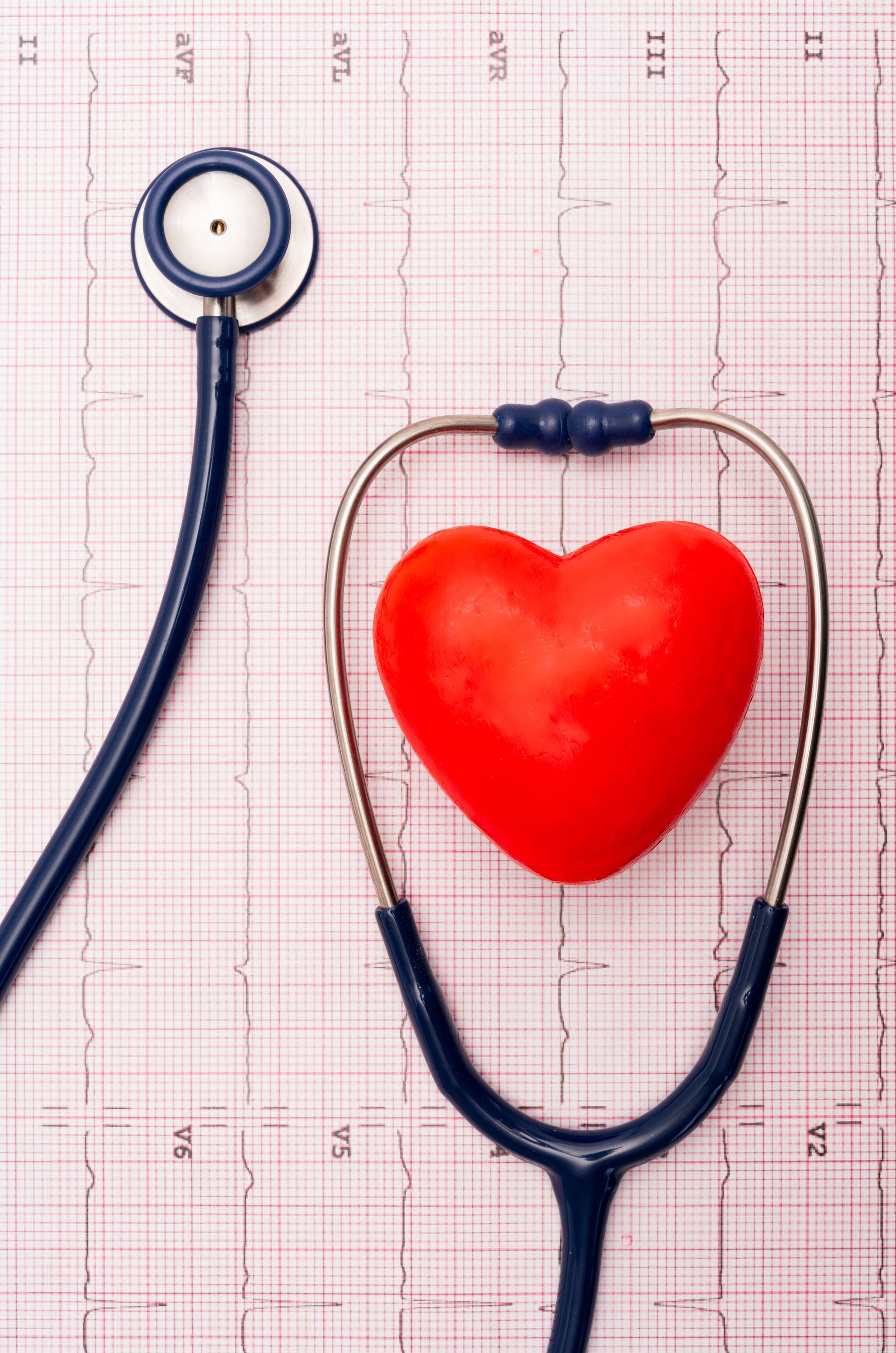 Top view of original composition made with a stethoscope and fake heart on a background of real electrocardiograms of patients having heart checkups